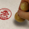 Toxic danger with skull stamp and stamping hand. Poison warning concept.