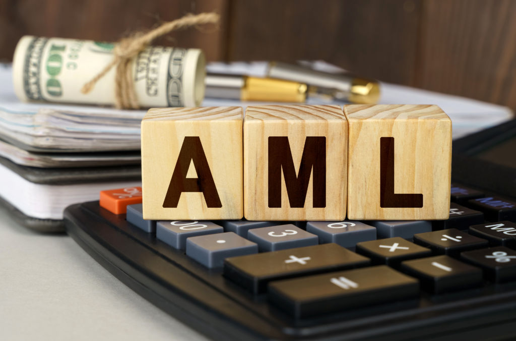 On the table are money, a calculator, a notebook and cubes with the inscription – AML FCA,AML,monzo,digital bank