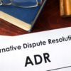 Papers with title Alternative Dispute Resolution (ADR) on a table.