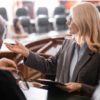 middle aged attorney pointing with hand near grey-haired judge in courtroom